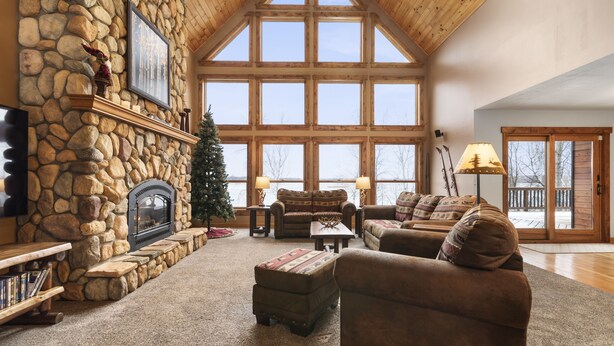 Una sala de estar acogedora con chimenea de piedra, ventanas amplias y asientos cómodos.