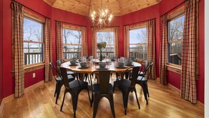 Comedor con techo de madera, paredes rojas y cortinas a cuadros.