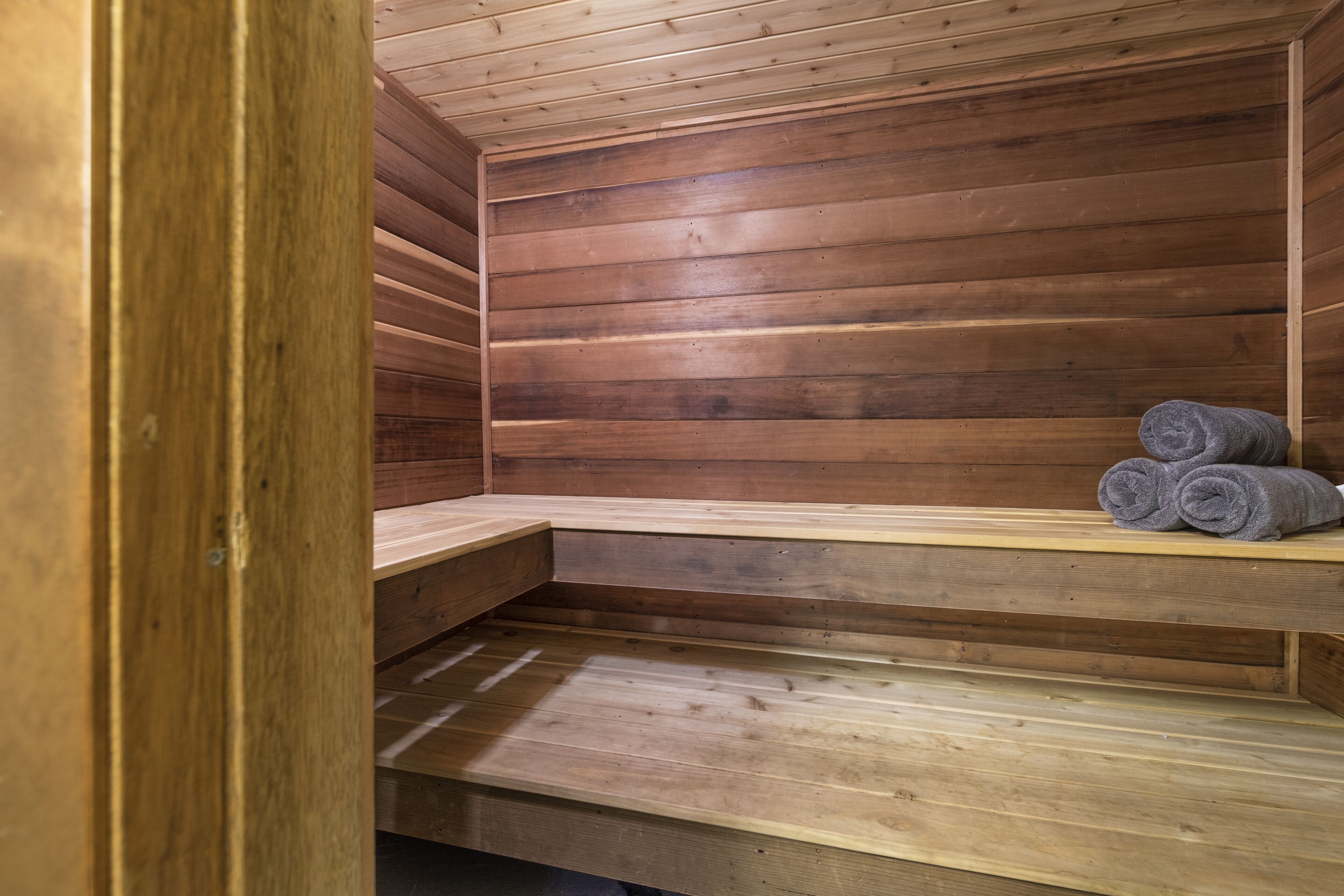 A wooden sauna with benches and a towel rack.