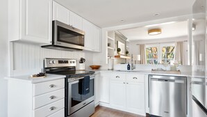 Una cocina moderna con armarios blancos, electrodomésticos de acero inoxidable y encimera de madera.