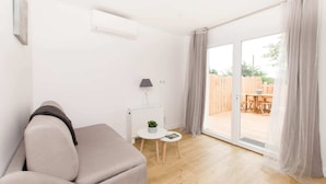 Una sala de estar moderna con un sofá, una mesita con lámpara y un ventanal corredero que da a un espacio exterior.