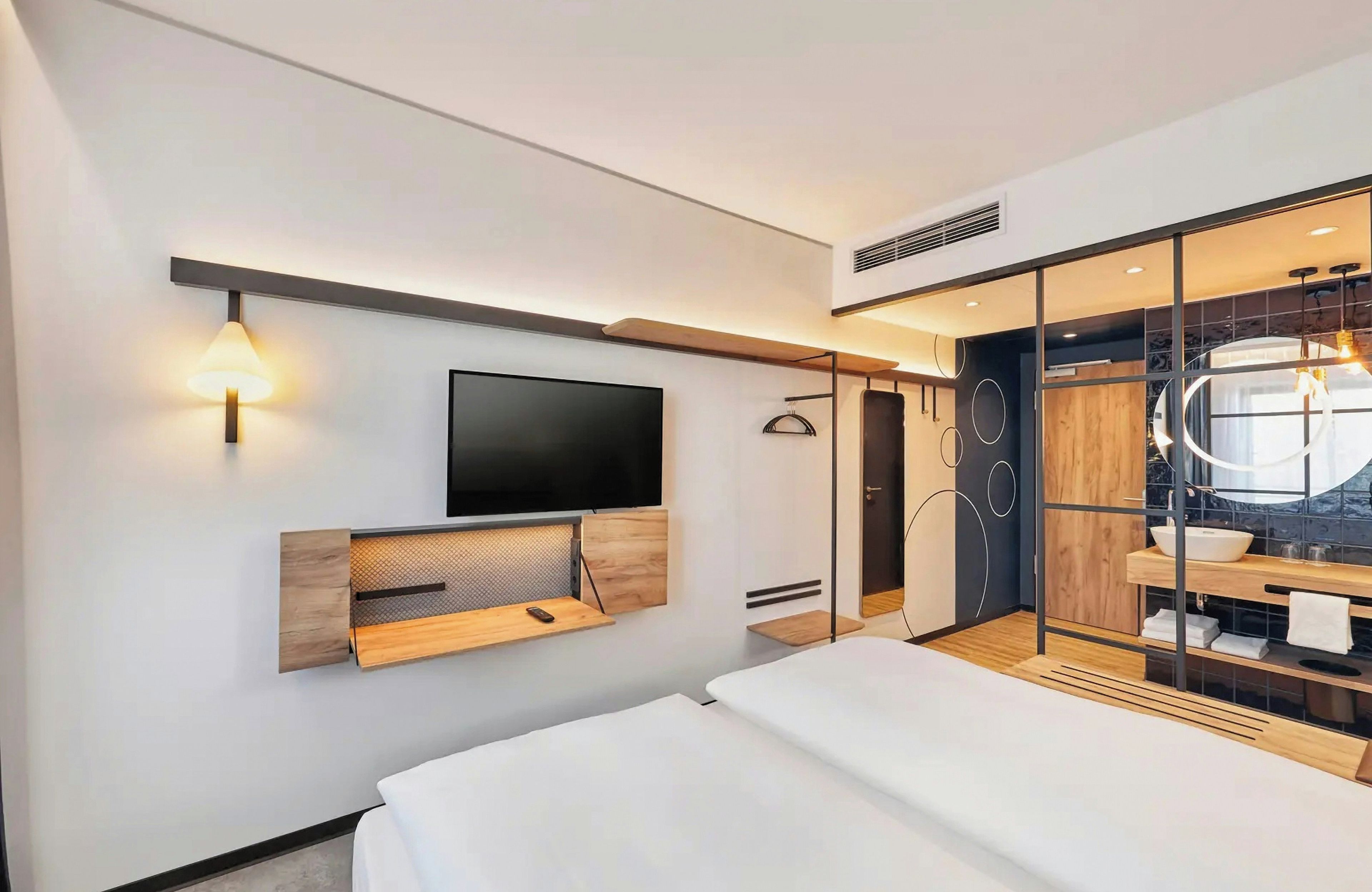 A modern bedroom with a bed, a mounted TV, and a built-in wardrobe with a mirror.