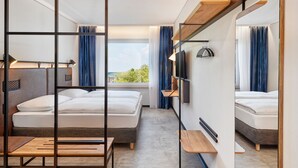 A modern hotel room with a large bed, a desk, a TV, and a window with a view of the outdoors. - H2 Hotel Düsseldorf City (Düsseldorf)