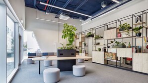 A modern office space with a long table, round seating, and shelves with plants. - H2 Hotel Düsseldorf City (Düsseldorf)