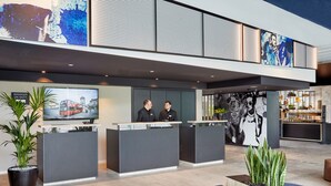 A modern hotel lobby with reception desks, large artwork, and indoor plants. - H2 Hotel Düsseldorf City (Düsseldorf)