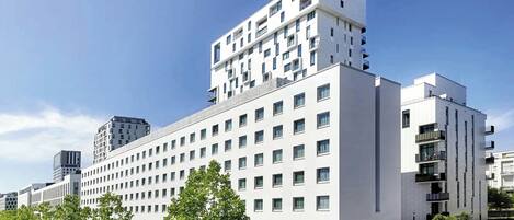 A modern multi-story building with a flat facade, numerous windows, and balconies.