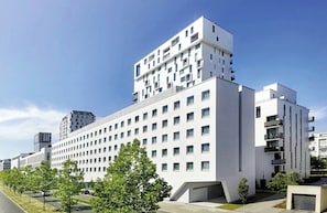 Un immeuble moderne à plusieurs étages, doté d’une façade plate, de nombreuses fenêtres et de balcons.