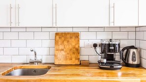 Une cuisine équipée d’un plan de travail en bois, d’une machine à café, d’une bouilloire et d’une planche à découper.
