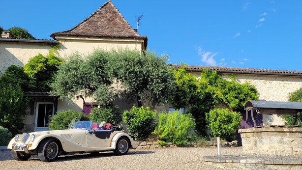 A beige convertible car parked in front of a house with a stone fountain and a small gazebo. - In the heart of Vineyards (LA REOLE)