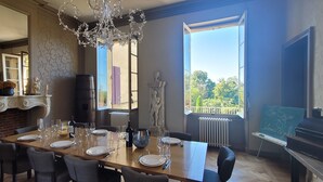 A dining room with a large table set for six, a fireplace, a piano, and a view of the outdoors. - In the heart of Vineyards (LA REOLE)