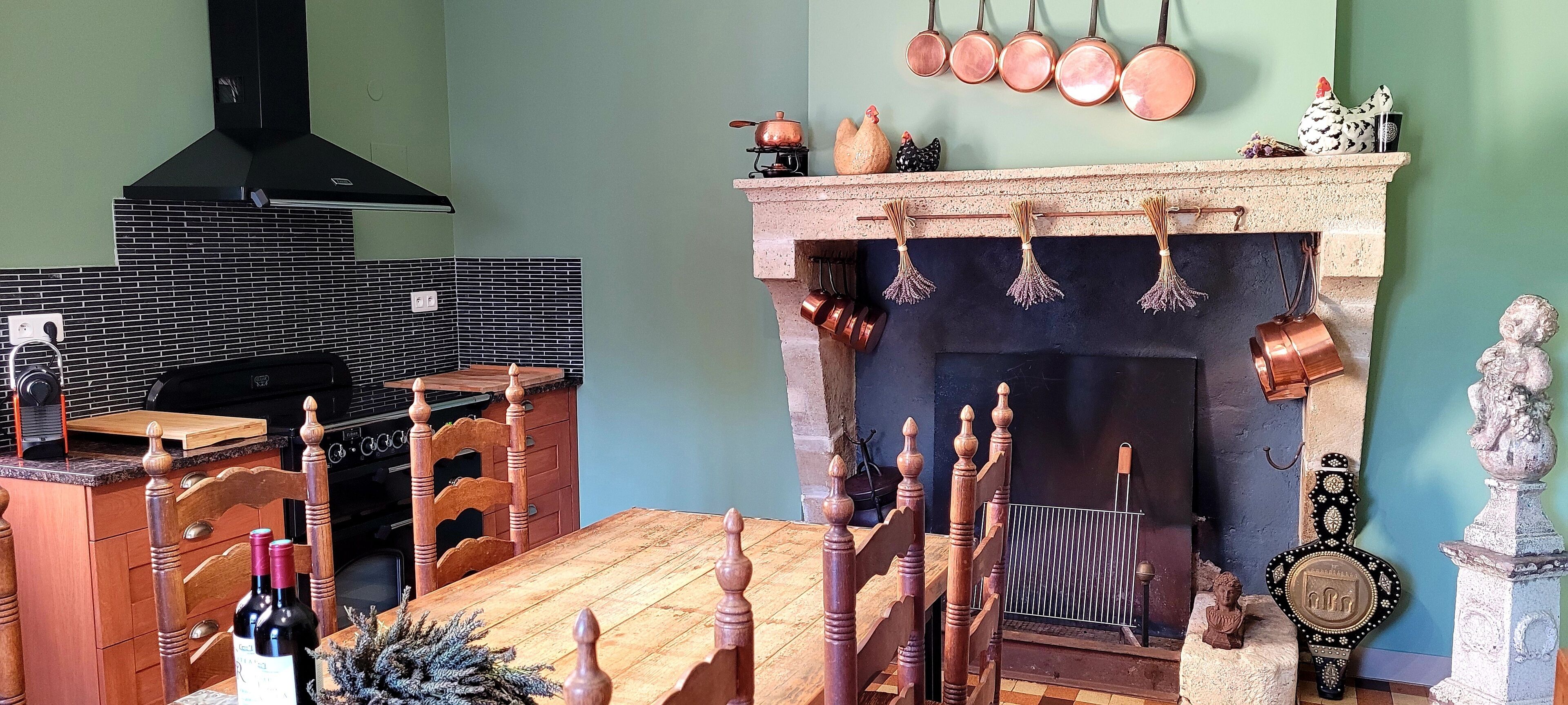 A kitchen with a wooden table, chairs, a stove, and a fireplace with hanging pots.