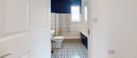 Un baño con inodoro, lavamanos y toallero.