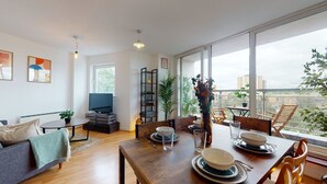 Un salon moderne avec un coin repas, de grandes fenêtres et une vue sur la ville.