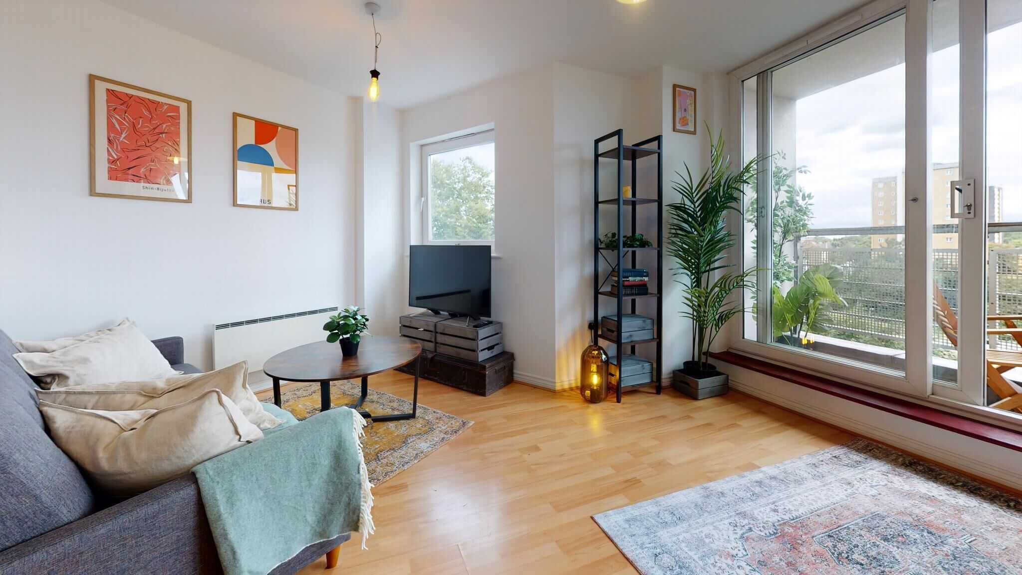 A modern living room with a sofa, TV, coffee table, and large windows.