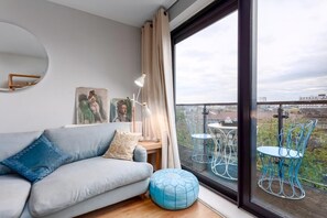 A modern living room with a sofa, a round mirror, a lamp, and artwork on the wall.