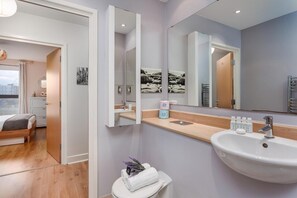 A modern bathroom with a sink, mirror, and toilet.