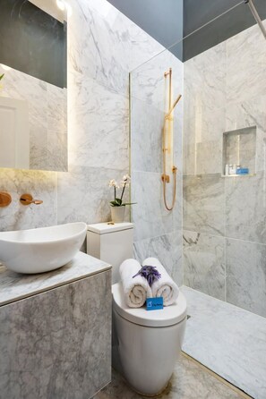 Ein modernes Badezimmer mit einem großen, weißen Waschbecken, einer Toilette und einer Duschkabine.