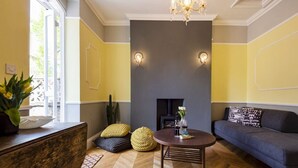 Uma sala de estar com lareira, um sofá, uma mesa de centro e piso de madeira.