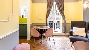 Quarto com uma mesa de jantar, duas cadeiras, um sofá e uma janela com cortinas.