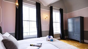 Quarto de hotel com uma cama grande, um guarda-roupa e uma janela com cortinas.