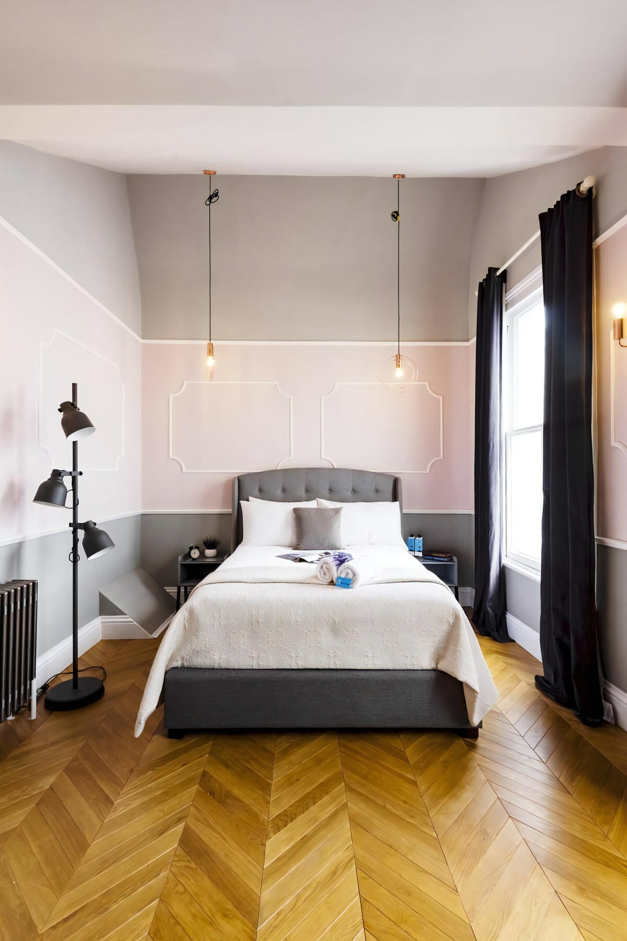 A modern bedroom with a large bed, a bedside table, a floor lamp, and a window with curtains.