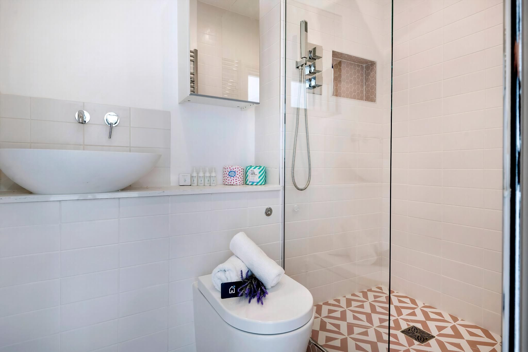 Ein modernes Badezimmer mit einem großen weißen Waschbecken, einer Glasdusche und einem WC mit einem Handtuch darauf.