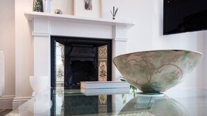 A modern living room with a fireplace, a large decorative bowl, and a book on a glass table. - Modern and Bright Highgate Gem (London)