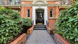 A building entrance with a black and white checkered floor, brick walls, and a sign above the door. - Stunning Maida Vale Apartment (London)