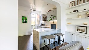 A modern kitchen with an island, bar stools, and a potted plant. - Stunning Maida Vale Apartment (London)