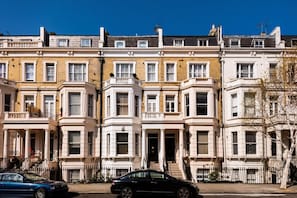 A row of terraced houses with a black car parked in front.