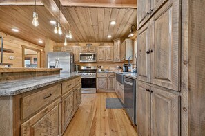 Una cocina con armarios de madera, electrodomésticos de acero inoxidable y encimera de mármol.