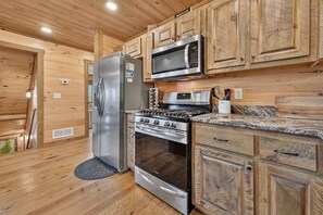 Une cuisine avec des meubles en bois, un réfrigérateur en acier inoxydable, un four à micro-ondes et une cuisini ère.