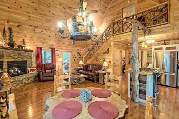 L’intérieur chaleureux d’un chalet en bois, avec une cheminée en pierre, des meubles en bois et un escalier menant à un étage supérieur.