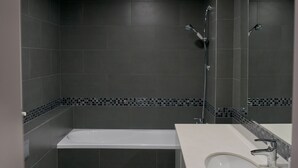 Ein modernes Badezimmer mit Badewanne, Toilette und Waschbecken.