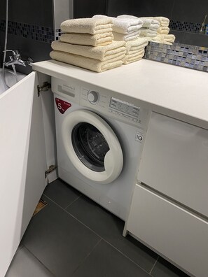 Laundry room with a front-loading washing machine and a standard faucet.