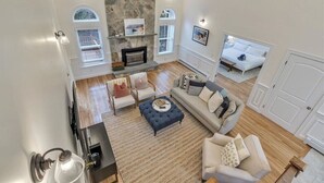 A spacious living room with a stone fireplace, a sofa, a coffee table, and a TV.