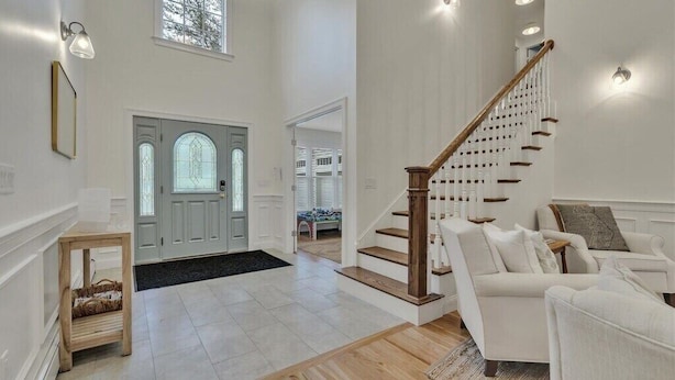 A spacious living area with a staircase, a white sofa, and a wooden floor.