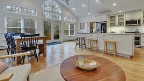 A spacious kitchen with white cabinets, a large island, and a dining area with a wooden table and chairs.