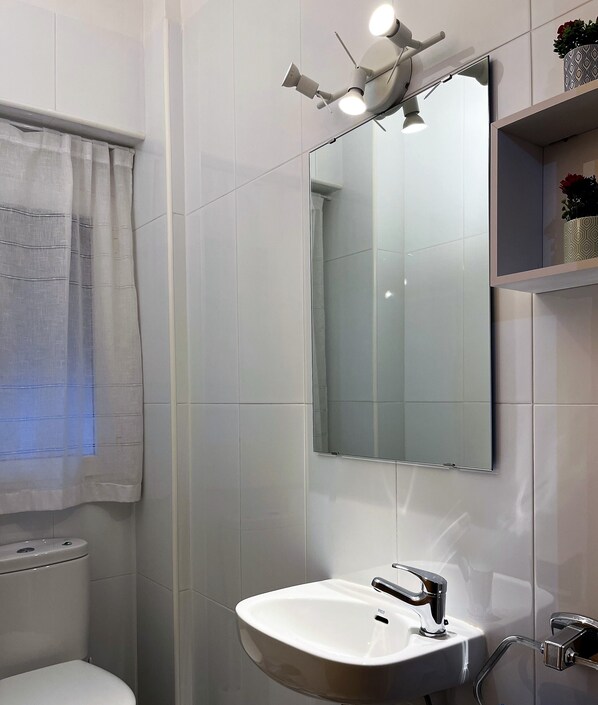 A modern bathroom with a white sink, a mirror, and a ceiling-mounted light fixture.
