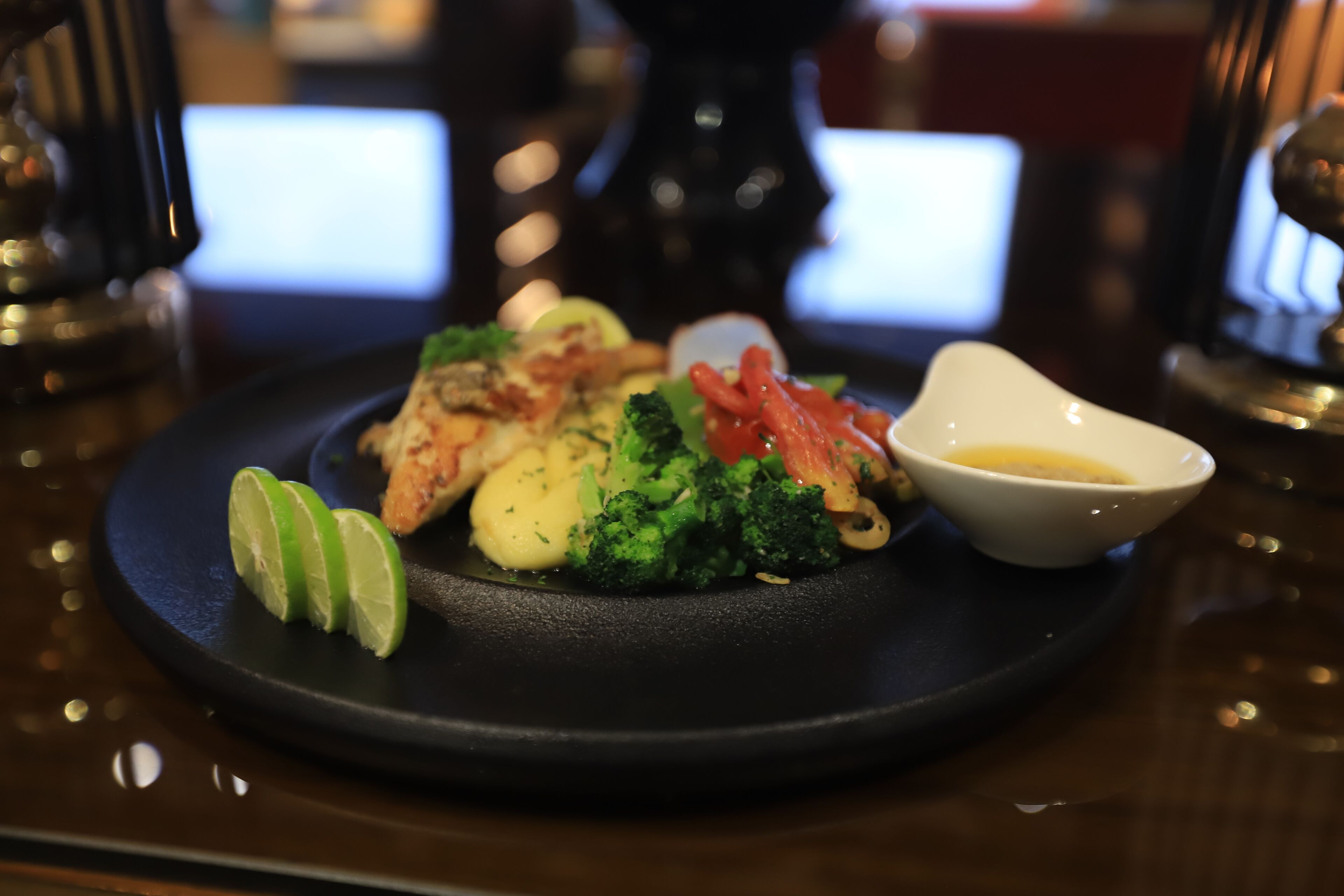 Une assiette de nourriture comprenant des brocolis, des crevettes et un petit bol de sauce.
