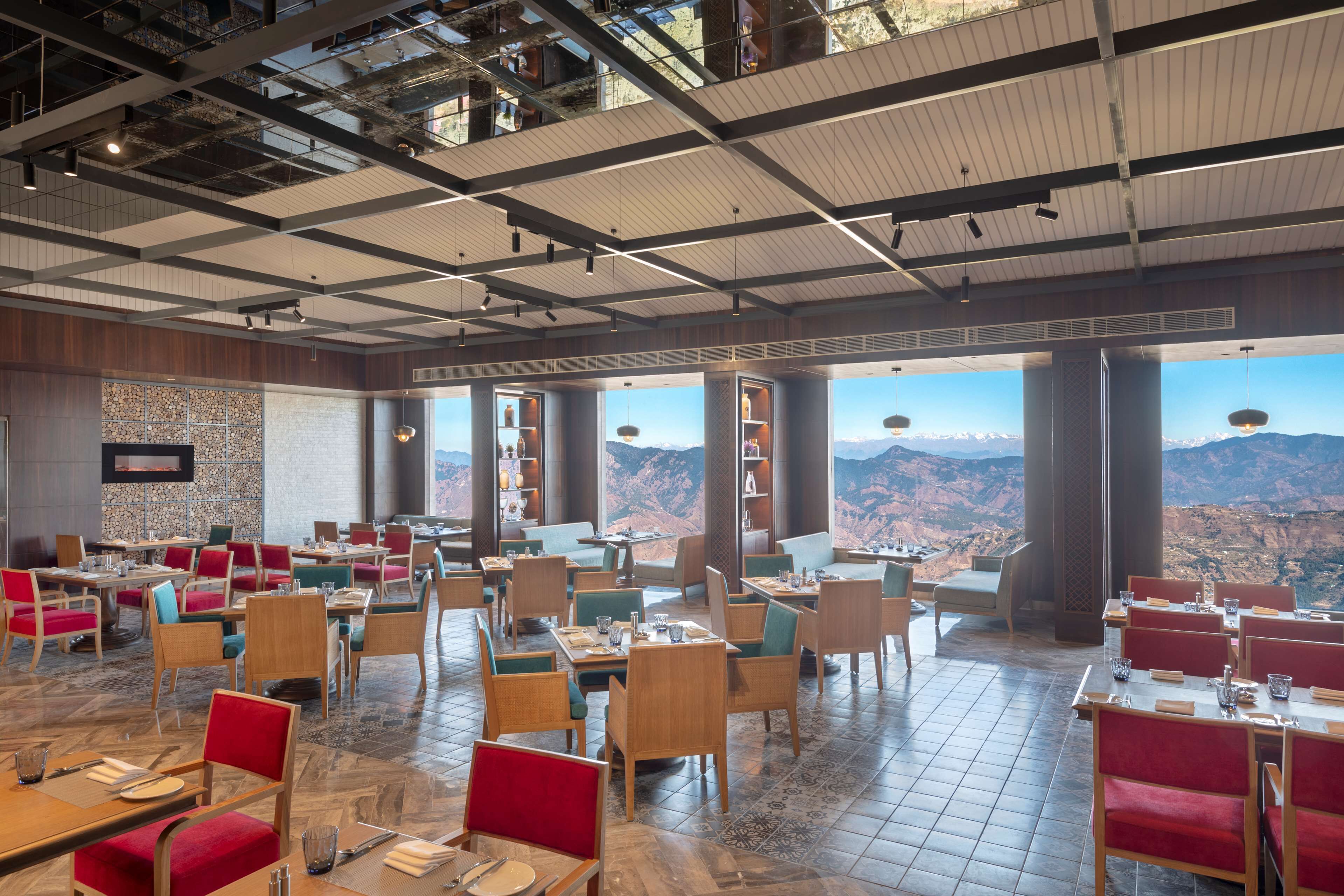 Een ruim restaurant met verschillende eetgedeeltes, grote ramen met uitzicht op de bergen, en een modern plafondontwerp.