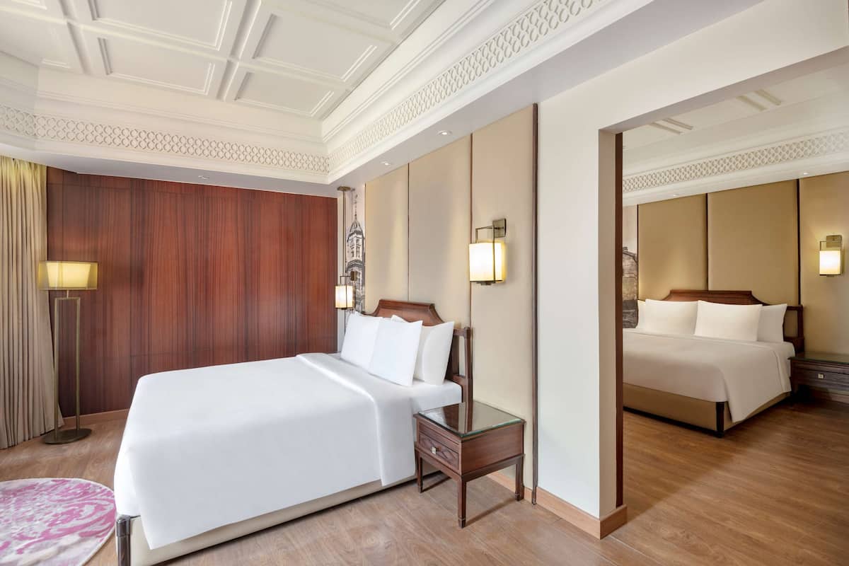 A hotel room with a large bed, a nightstand, a lamp, and a mirror.