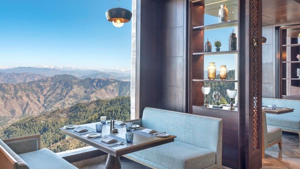 A modern interior with a dining area, seating, and a view of the mountains. - Radisson Hotel Kufri Shimla (Theog)