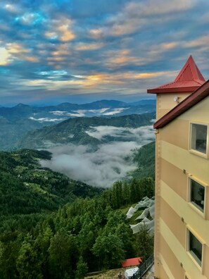 A mountain view with a building featuring a red roof and multiple windows.