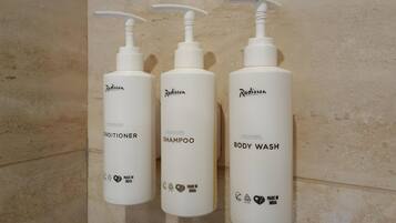 Three white bottles of Radisson toiletries on a tiled wall.