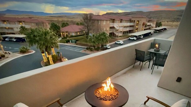 A balcony with a fire pit, outdoor seating, and a view of a parking lot and buildings. - New TownHome w/ Heated Pool & Hot Tub in St.George (St. George)