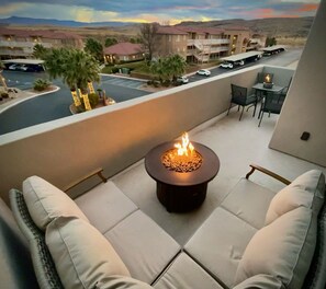 A balcony with a fire pit, outdoor seating, and a view of a parking lot and buildings. - New TownHome w/ Heated Pool & Hot Tub in St.George (St. George)