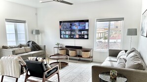 A modern living room with a flat-screen TV, two sofas, a coffee table, and a side table with a lamp. - New TownHome w/ Heated Pool & Hot Tub in St.George (St. George)