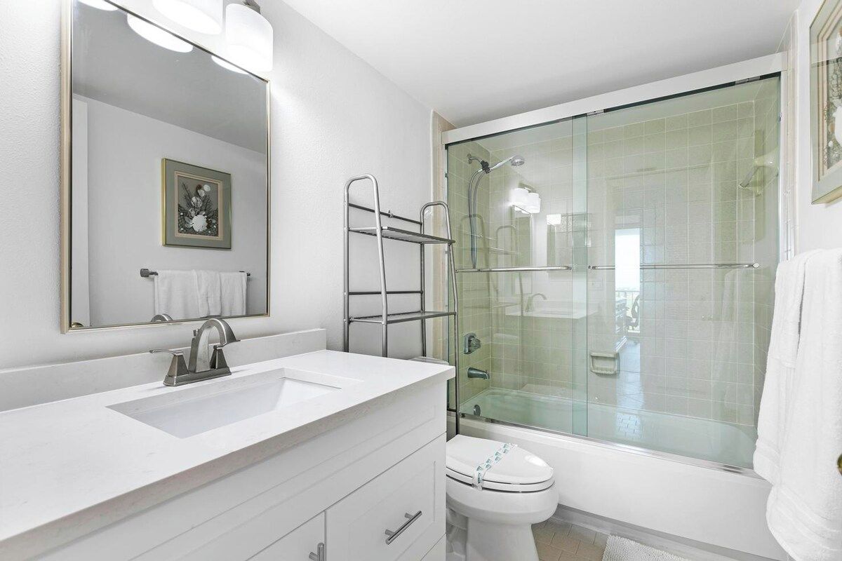 Une salle de bain moderne avec un lavabo blanc, un miroir et une douche à parois de verre.