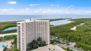 A high-rise hotel with multiple floors, a swimming pool, and a view of the ocean and a mangrove-lined beach. - South Seas Retreat Beachfront 2BD/2BA- Gulf Views (Marco Island)